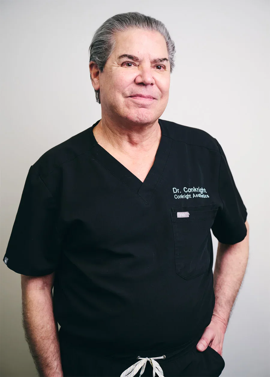 Doctor James Micheal Conkright MD in black medical scrubs standing against white background for professional portrait - Doctor in Evansville, IN