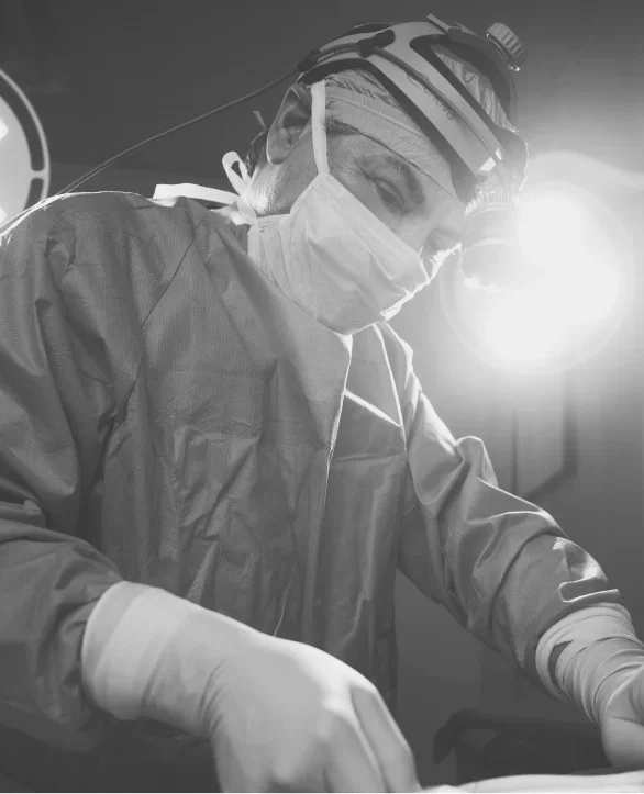Doctor James Micheal Conkright MD performing operation in sterile gown and headlamp in black and white photograph - in Evansville, IN