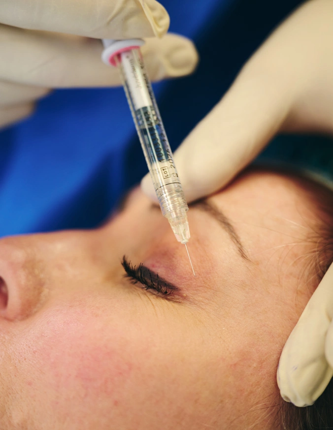 Cosmetic professional administering dermal filler injection to woman's forehead for wrinkle reduction treatment - Botox and wrinkle relaxers in Evansville, IN