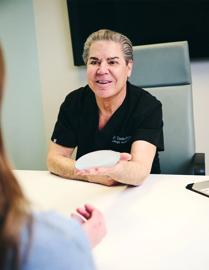 Healthcare professional in black scrubs consulting with patient at desk in medical office - Breast augmentation in Evansville, IN