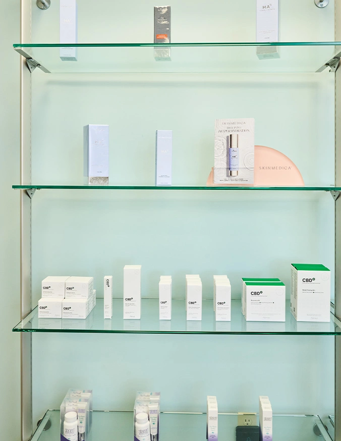 Glass shelves displaying white skincare product bottles and containers in modern minimalist retail setting - Medical grade skincare in Evansville, IN