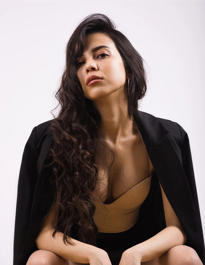Woman with long dark hair in black blazer and tan top posing against white background - Sculptra in Evansville, IN